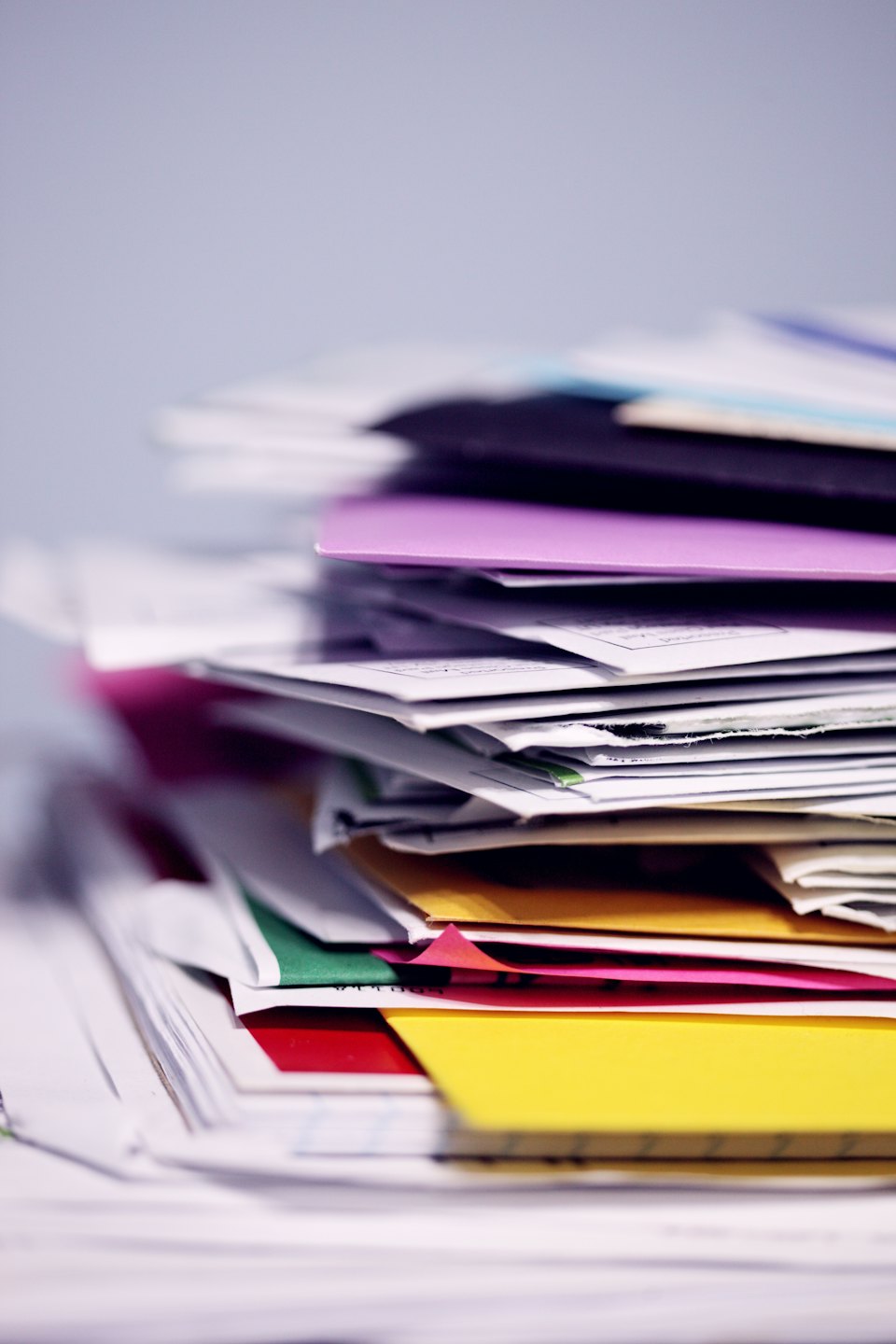 A messy pile of papers and file folders on a desk.